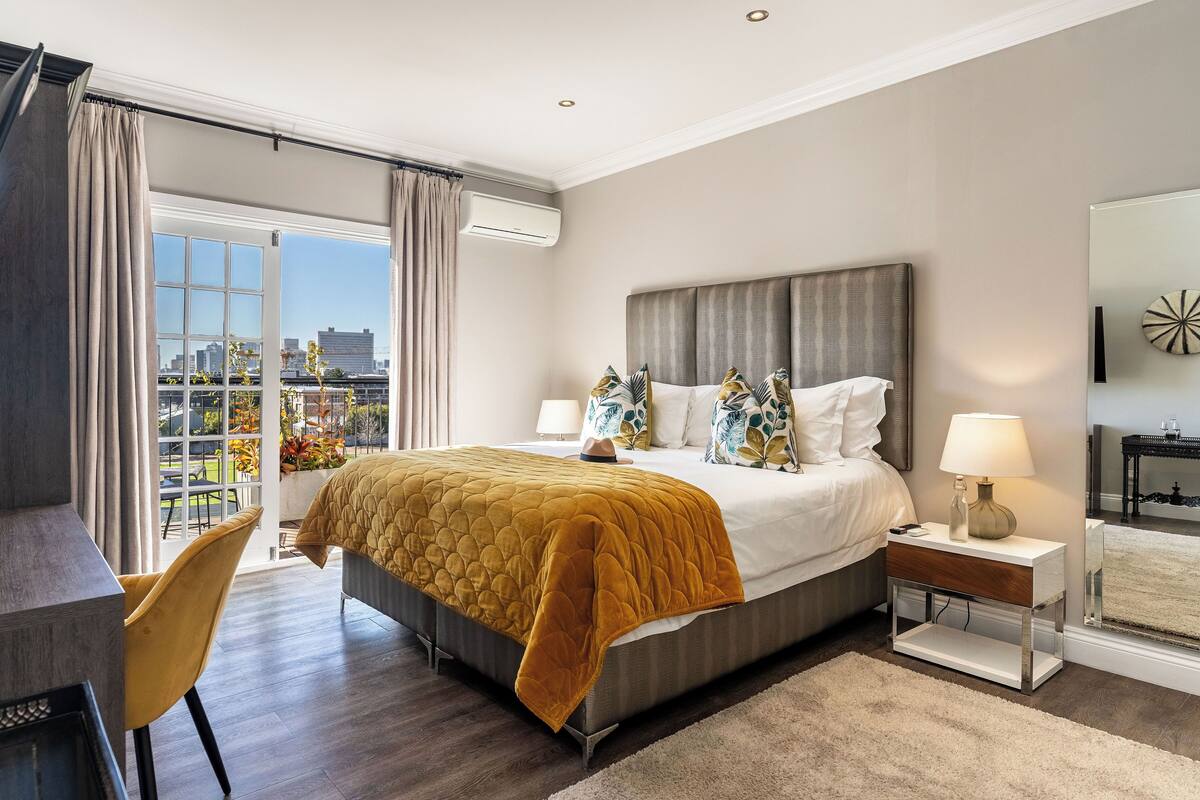 A modern hotel room with a large bed, a desk, and a view of the city.