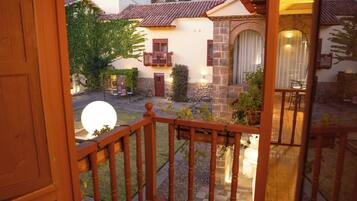 Un balcone in legno con vista su una zona residenziale, tra case e una collina.