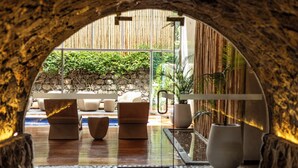 A stone archway leading to a seating area with sofas and a small pool. - Casa Cartagena Boutique Hotel & Spa (Cusco)