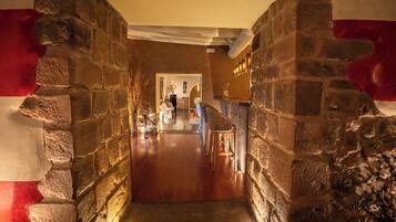 A stone-walled corridor with a wooden floor leading to a reception area.