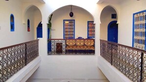A courtyard with arches, a central fountain, and a balcony with ornate railings.