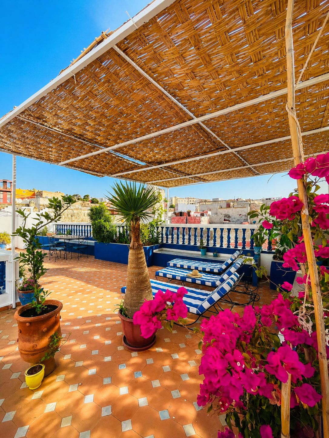 Un patio al aire libre con techo de paja, suelo de baldosas y mobiliario exterior.