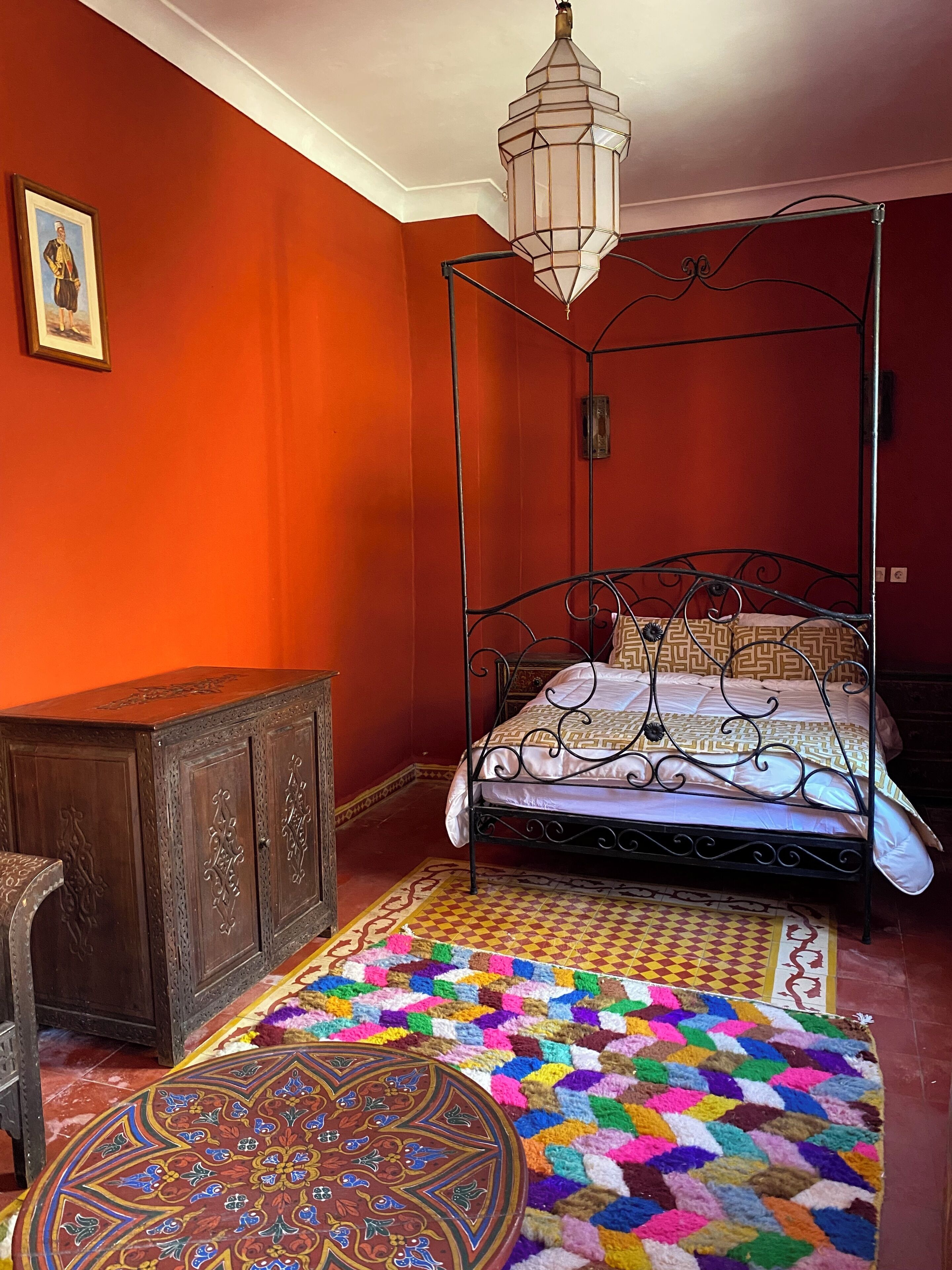 Une chambre à coucher avec un lit à baldaquin, une armoire en bois et un tapis coloré.