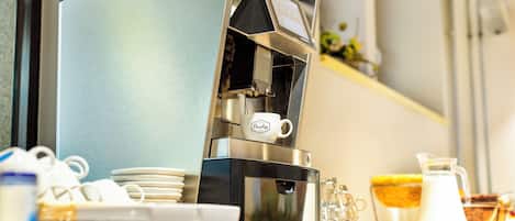 A coffee machine with a milk frother, a coffee pot, and a milk jug on a counter.