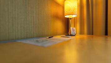 Una habitación de hotel con una lámpara sobre una mesa de madera, un bloc de notas y un bolígrafo.