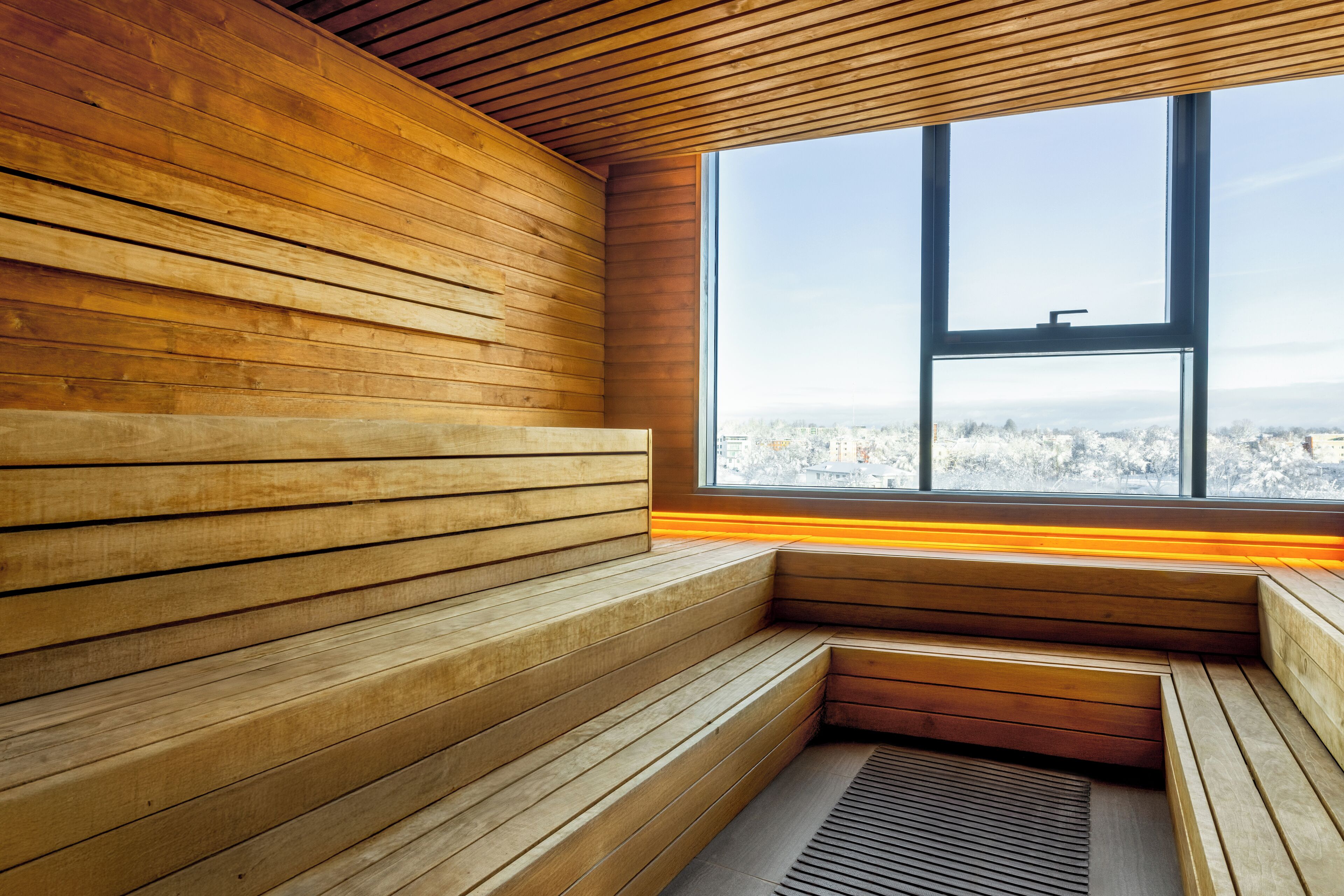 Zona con bancos de madera y un amplio ventanal con vista a la ciudad.