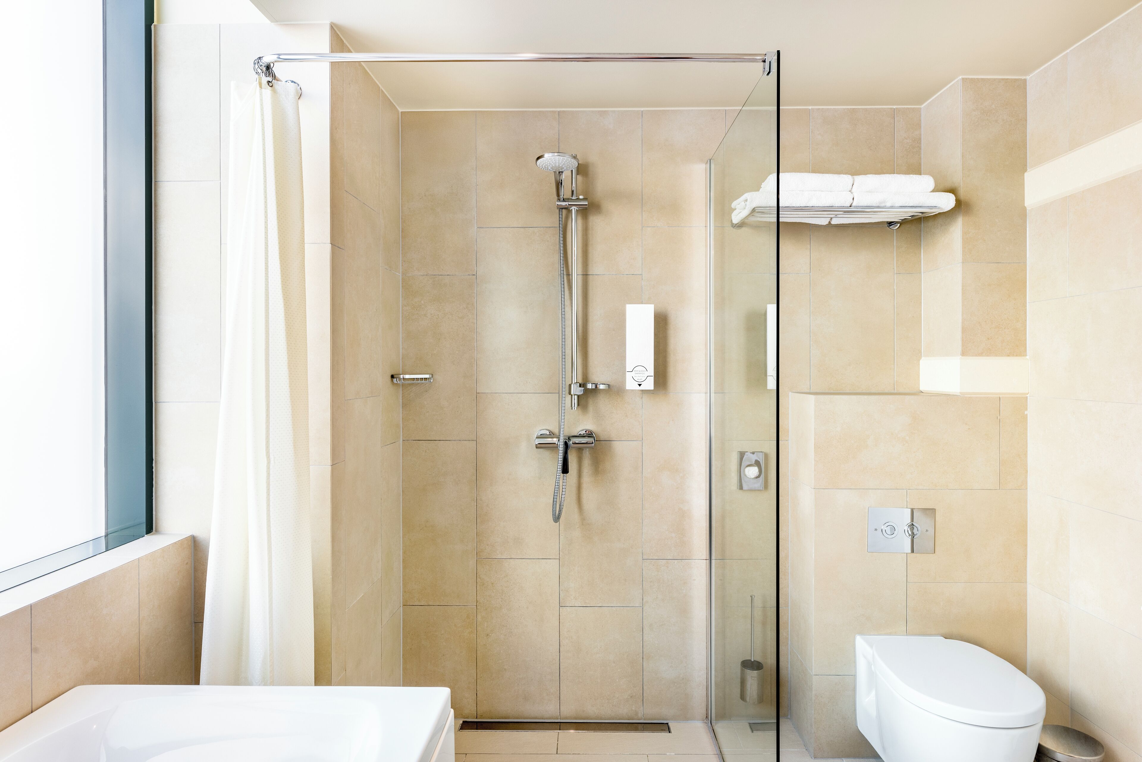 Un baño moderno con ducha acristalada, inodoro blanco y bañera.