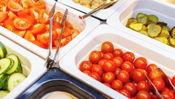 A buffet with various food items including sliced tomatoes, cucumbers, and cherry tomatoes.
