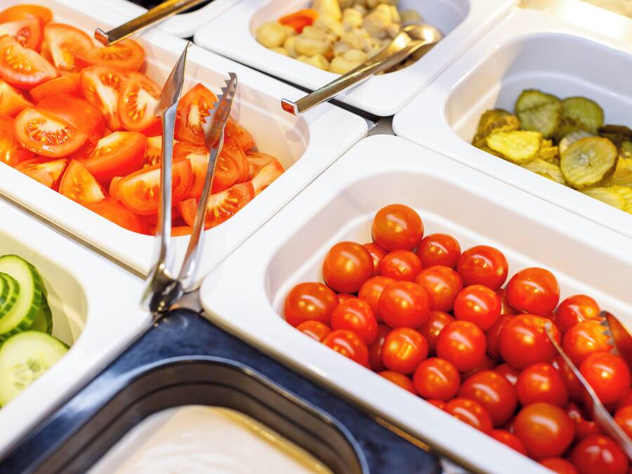 A buffet with various food items including sliced tomatoes, cucumbers, and cherry tomatoes.