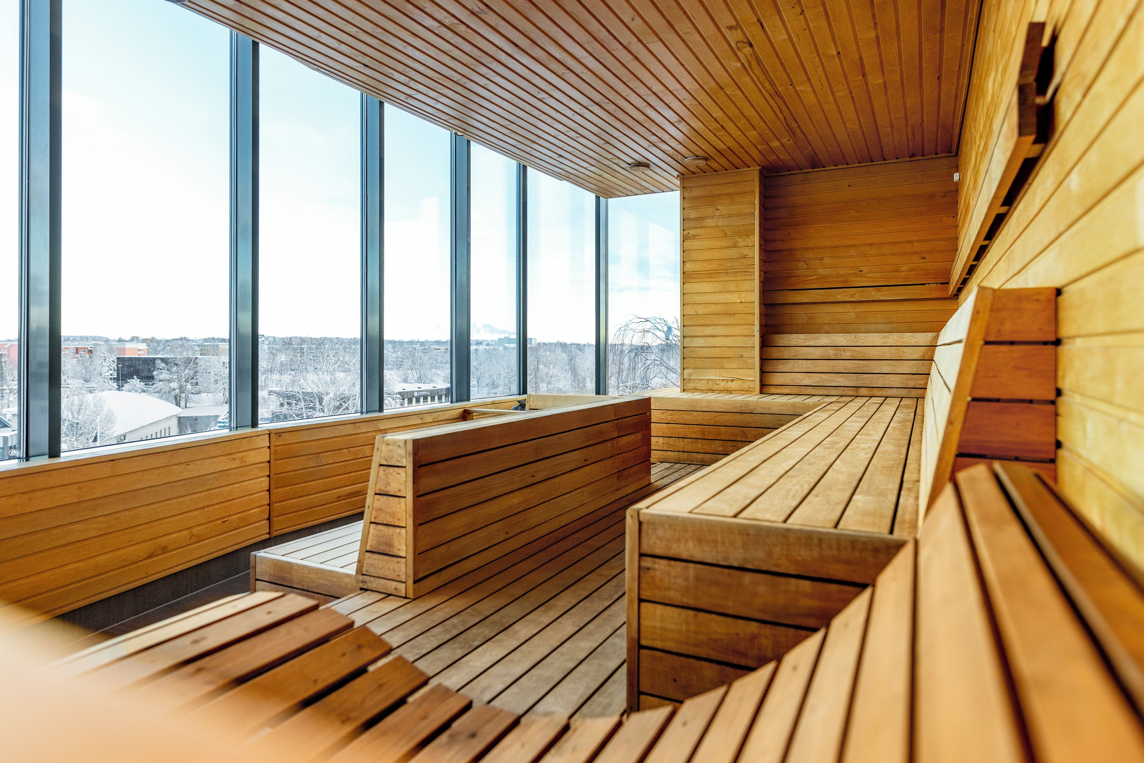 Un interior moderno con bancos de madera y ventanas amplias que ofrecen vistas a la ciudad.