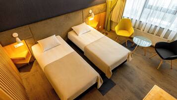 Habitación de hotel con dos camas, una mesita, una silla y una lámpara.