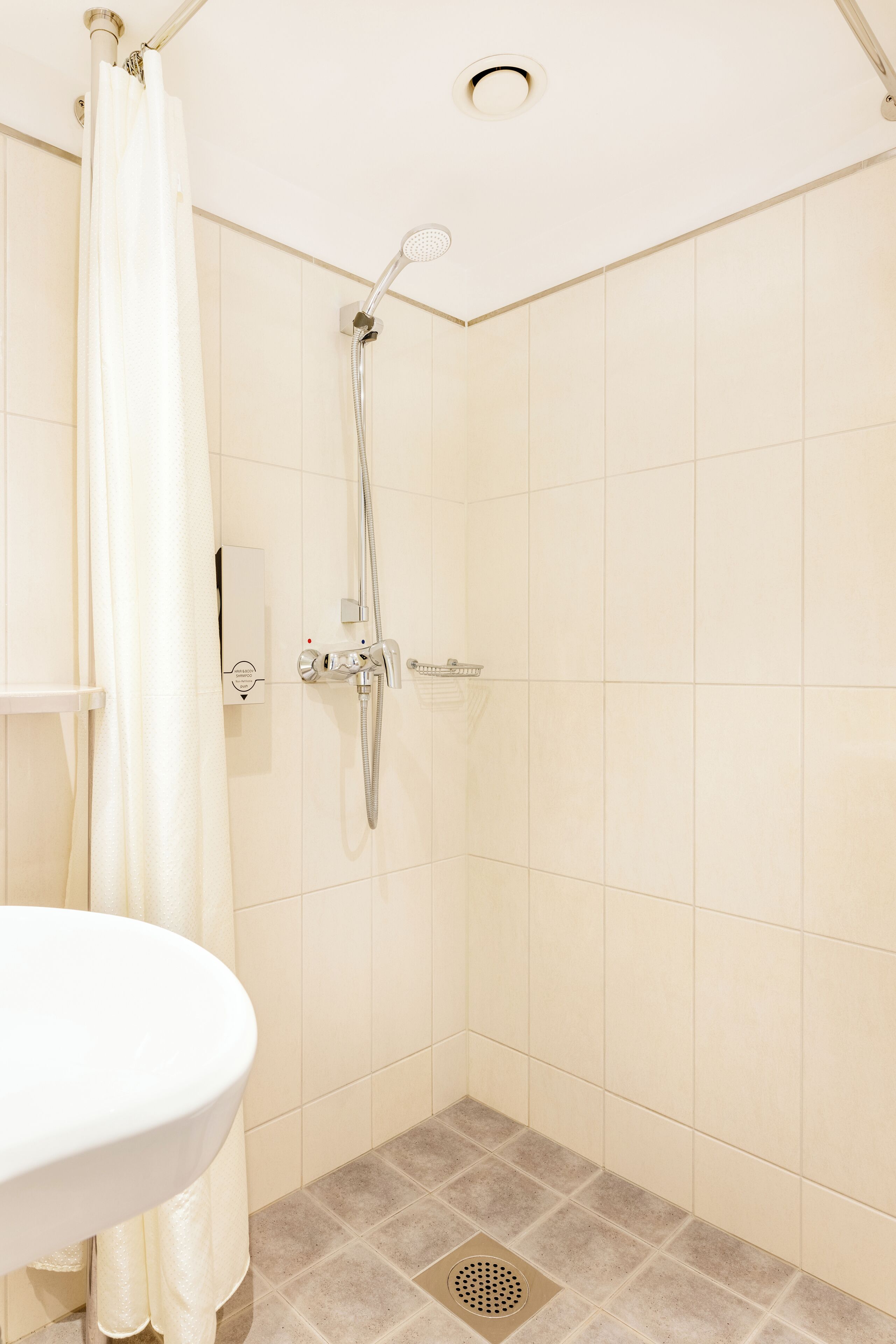 Un baño pequeño y limpio con ducha, lavamanos e inodoro.