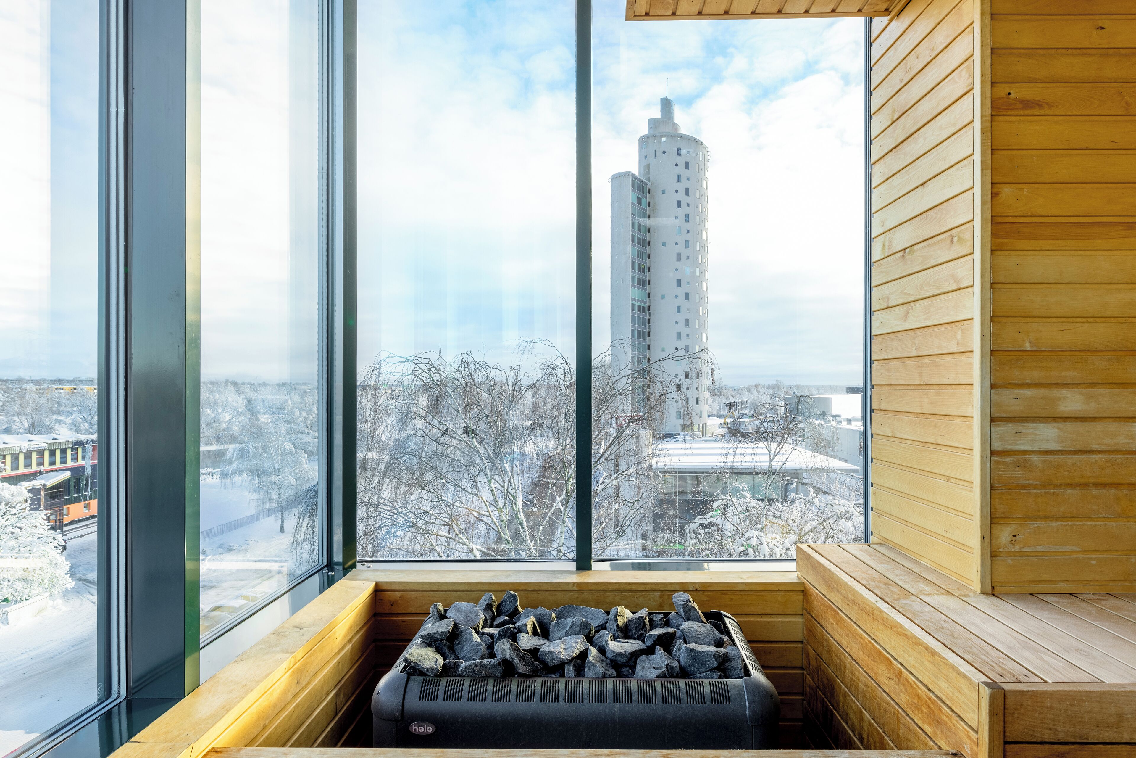 Un sauna avec vue sur un grand immeuble et des arbres couverts de neige.