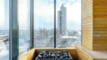 Eine Sauna mit Blick auf ein hohes Gebäude und schneebedeckte Bäume.