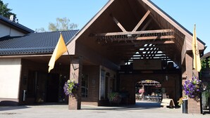 A building with a covered entrance, outdoor seating, and hanging flower baskets.