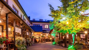 A courtyard with a restaurant, outdoor seating, and a tree with illuminated lights.