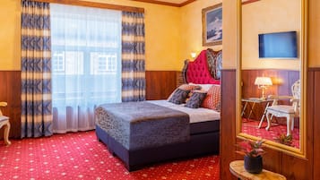 Habitación de hotel con una cama grande, una mesita con una lámpara, una silla y un espejo amplio.
