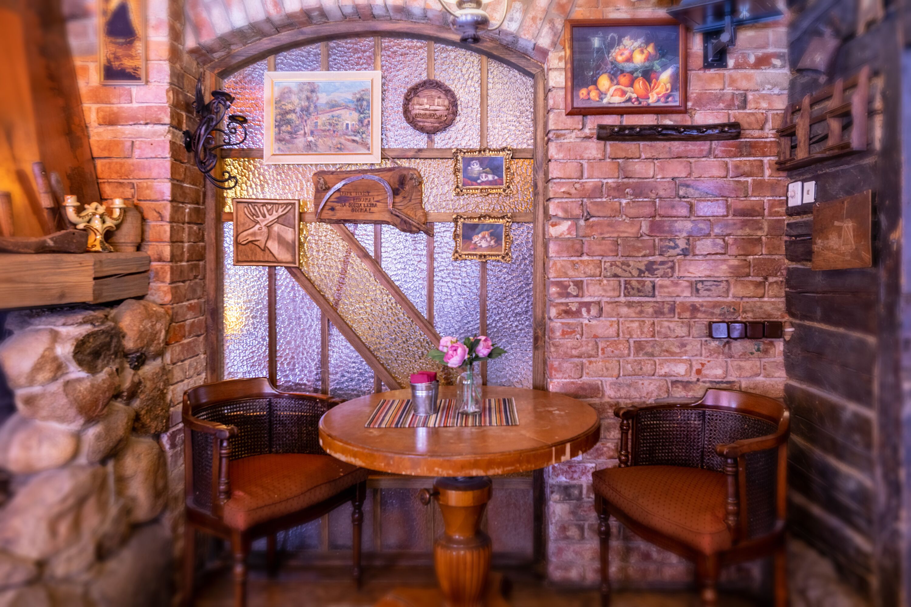 Ein rustikales Interieur mit Backsteinwand, Holzmöbeln und dekorativen Elementen wie gerahmten Bildern und einem Holzschild.