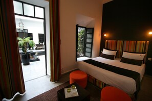 A hotel room with a bed, a small table with a tray, and a view of the outside balcony. - Riad Villa Wengé (Marrakech)