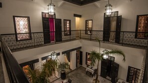 A multi-level interior with a balcony, potted plants, and a dining area. - Riad Villa Wengé (Marrakech)