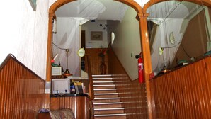 Een statige trap met een kroonluchter, houten lambrisering en een rood plafond.