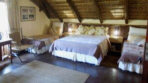 A room with two beds, a wooden ceiling, and a table with chairs. - Trees Too Guest Lodge (Nkomazi)