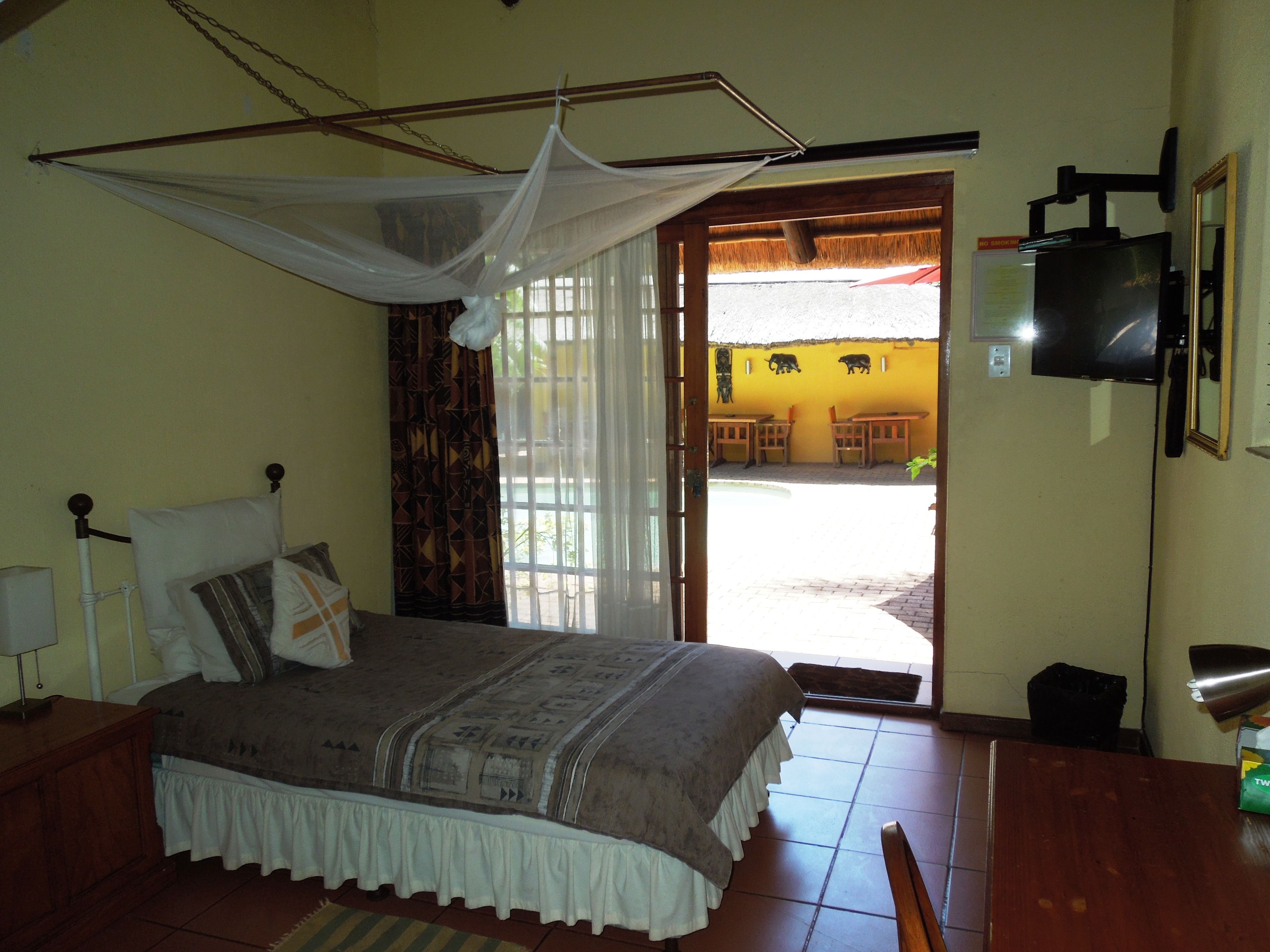 A bedroom with a bed, a TV, and a view of the outside.