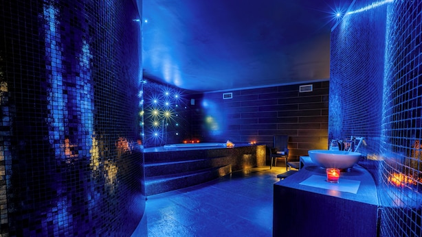 Um spa moderno com parede de mosaico, hidromassagem e área de pia.