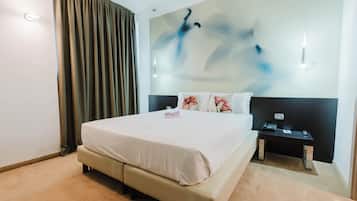 Une chambre d’hôtel avec un grand lit, une table de chevet avec un téléphone et un mur orné d’un tableau abstrait moderne.