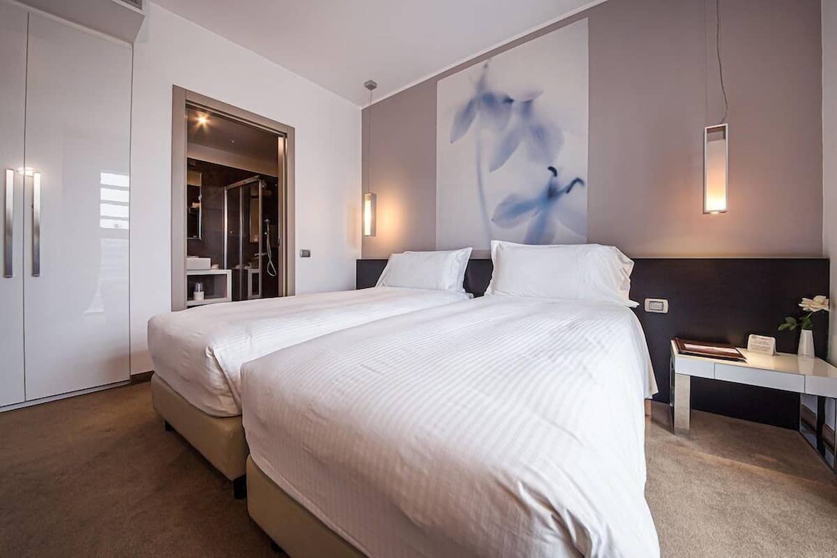 Une chambre d’hôtel moderne dotée d’un grand lit, d’un dressing et d’une œuvre d’art accrochée au mur.