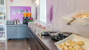 A buffet area with various food items and beverages, a no-smoking sign, and a wall with abstract art.