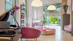 Um interior moderno com um piano de cauda, uma poltrona rosa e uma área de estar circular.