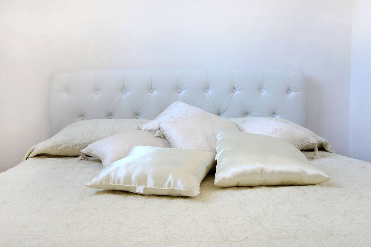 A bed with a tufted headboard and multiple pillows.
