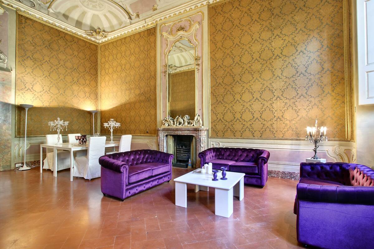 A spacious room with a fireplace, two purple sofas, a white coffee table, and a large mirror.