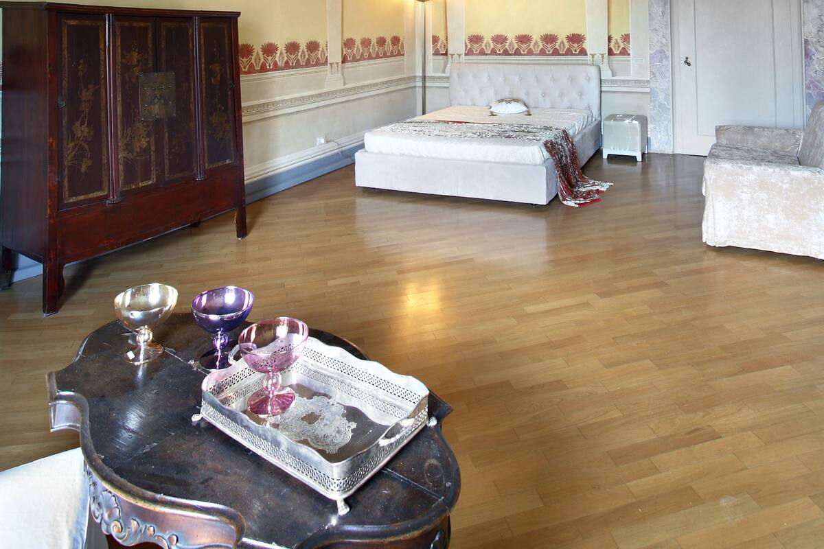 A room with a large bed, a wooden cabinet, and a table with decorative items.