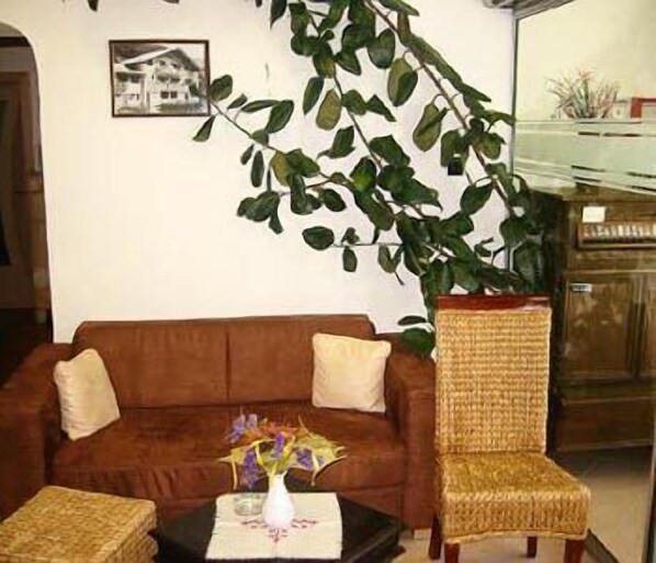 Un salon avec un canapé marron, un fauteuil en osier et une table sur laquelle est posé un vase de fleurs.
