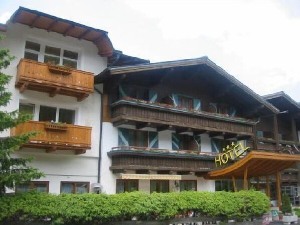 Een hotel met meerdere balkons, een overdekte ingang en een bord met Chinese karakters.