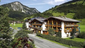 Un hôtel de style alpin traditionnel, doté d’un balcon imposant et offrant une vue imprenable sur les montagnes.