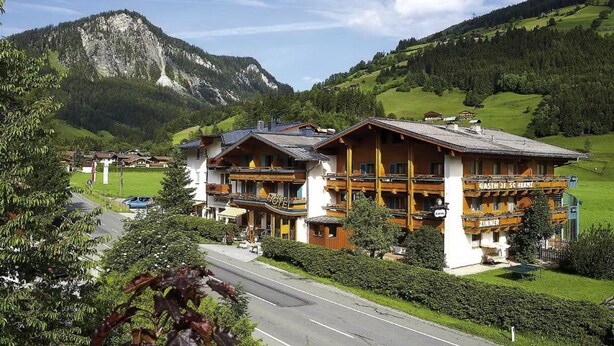 Un hôtel de style alpin traditionnel, doté d’un balcon imposant et offrant une vue imprenable sur les montagnes.