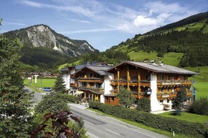 Un hôtel de style alpin traditionnel, doté d’un balcon imposant et offrant une vue imprenable sur les montagnes.