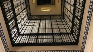 A room with a tiled floor, a window with curtains, and a small vent.