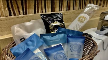 Ein Korbwäscher mit Toilettenartikeln, darunter eine weiße Tasche, eine schwarze Tasche und mehrere blaue Säckchen mit dem Aufdruck „Hotel Europa Sevilla Gel & Champú“.