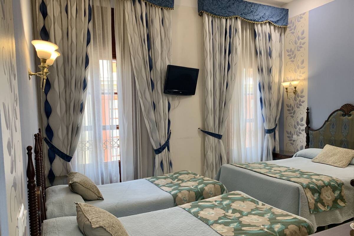 A hotel room with two beds, a television, and curtains.