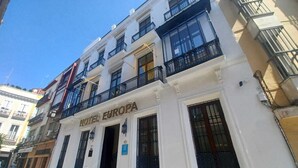 A two-story building with the sign "HOTEL EUROPA" indicating it is a hotel. The facade has multiple windows with black railings, and there are steps leading to the entrance.