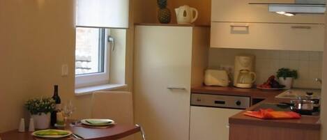 A compact kitchen with a refrigerator, a coffee maker, and a dining area with a table and chairs.