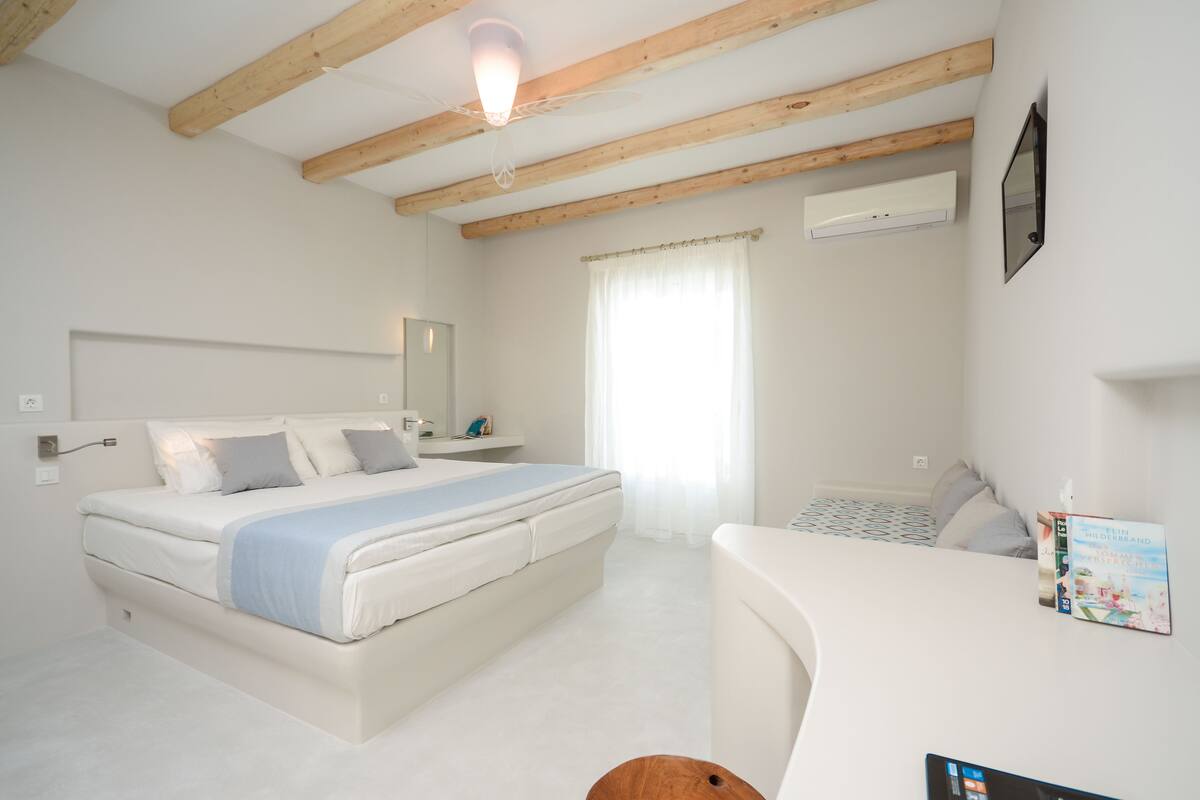 A bedroom with a bed, a desk, and a window.