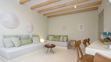 Ein modernes Wohnzimmer mit einem weißen Sofa, einem runden Couchtisch und Holzstühlen.