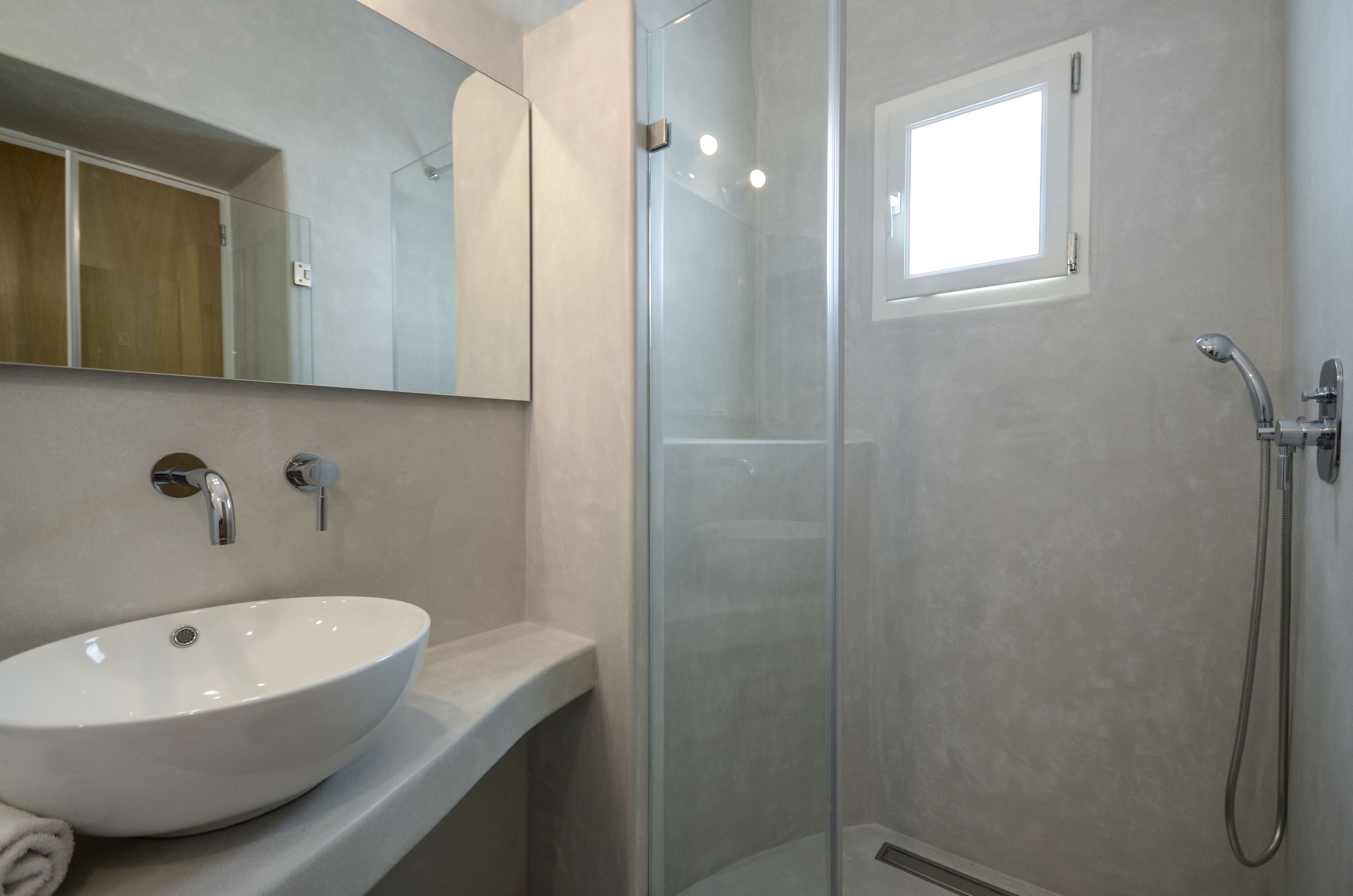 A bathroom with a white sink, a glass shower enclosure, and a mirror above the sink.
