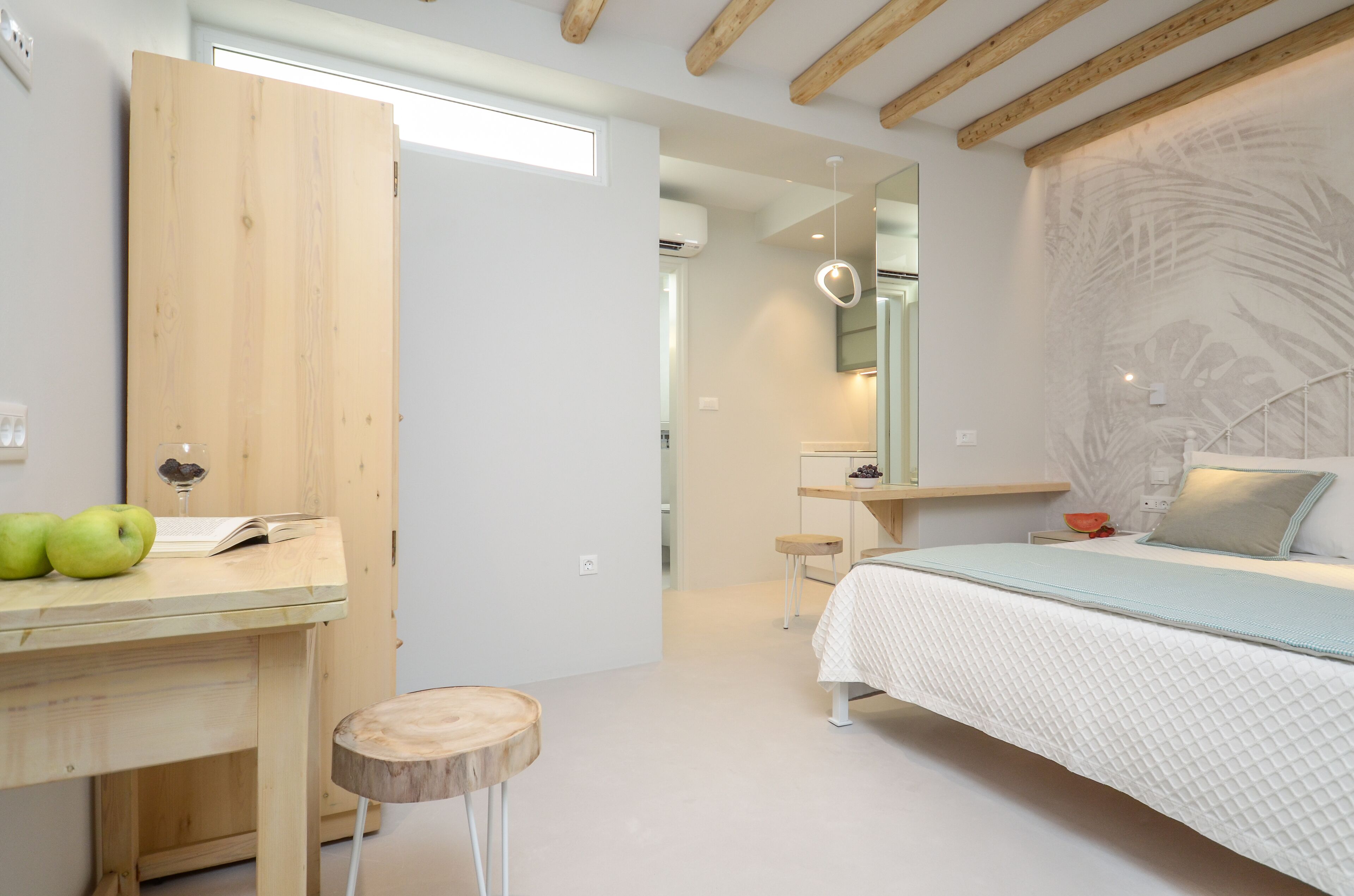 Une chambre moderne avec un bureau en bois, un lit recouvert d’une couette blanche et une grande fresque murale.