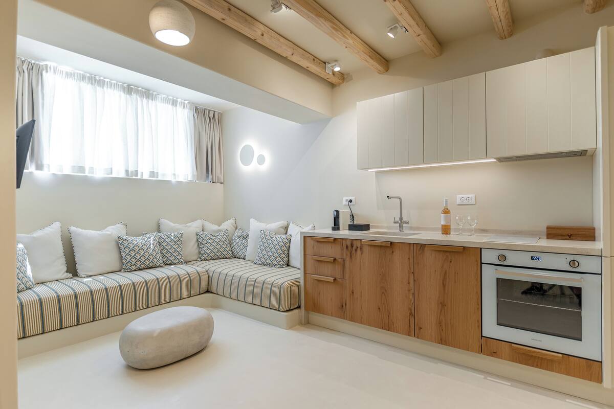 A modern kitchen with wooden cabinets, a built-in oven, and a seating area with a bench and cushions.